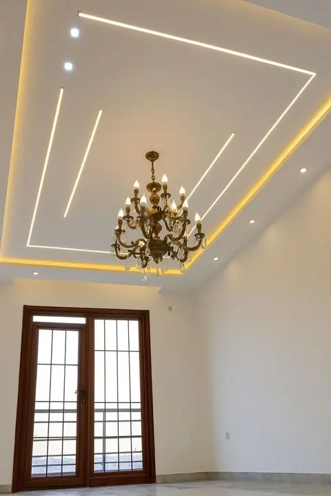 Teto com perfis de LED embutidos e sanca iluminada ao redor de um lustre